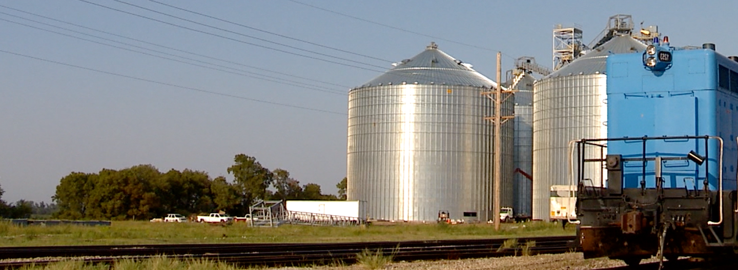 Train tracks in front of large grain silos.